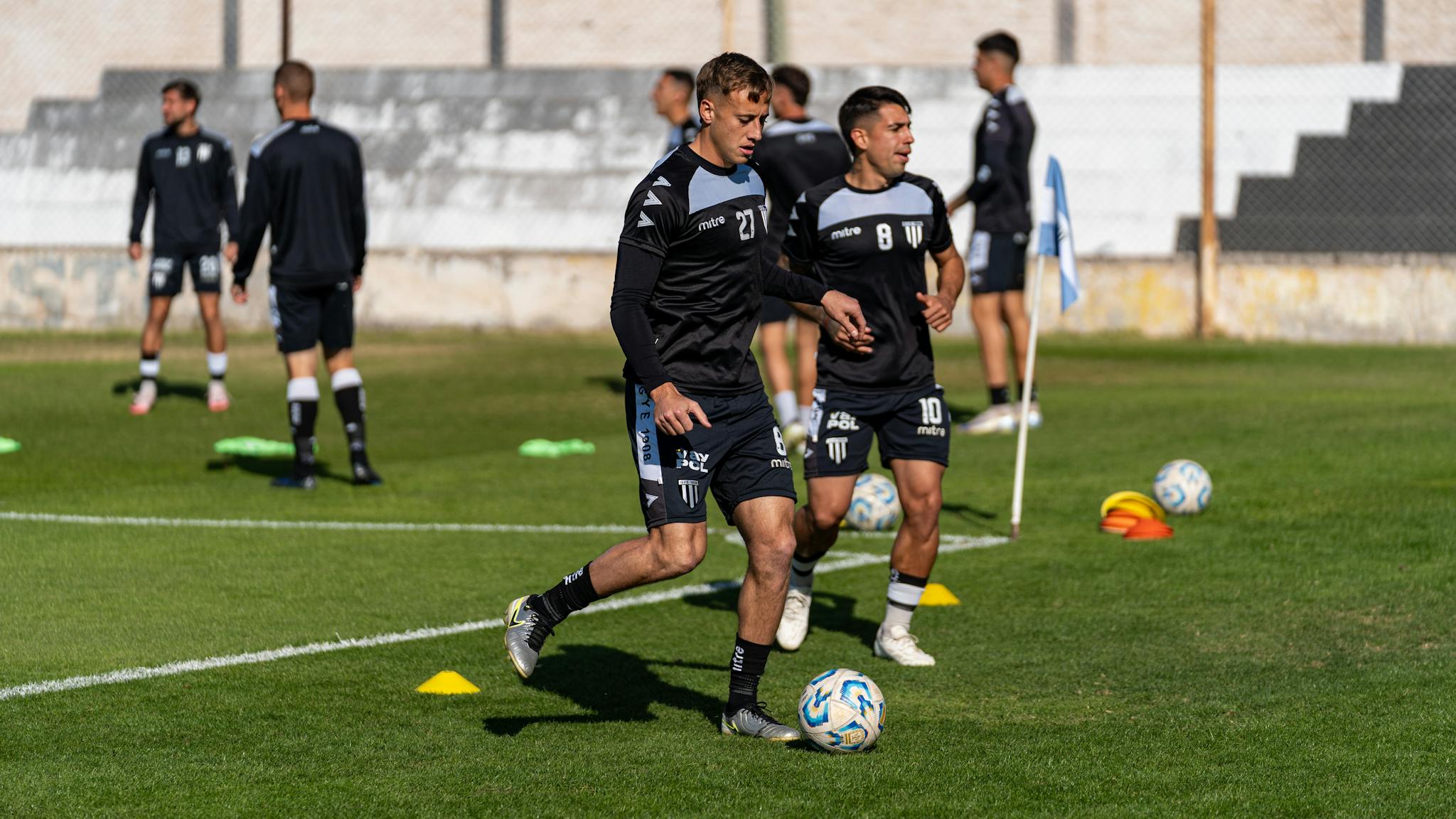 Group of young football players practicing on a sunny field, showcasing teamwork and skill development.